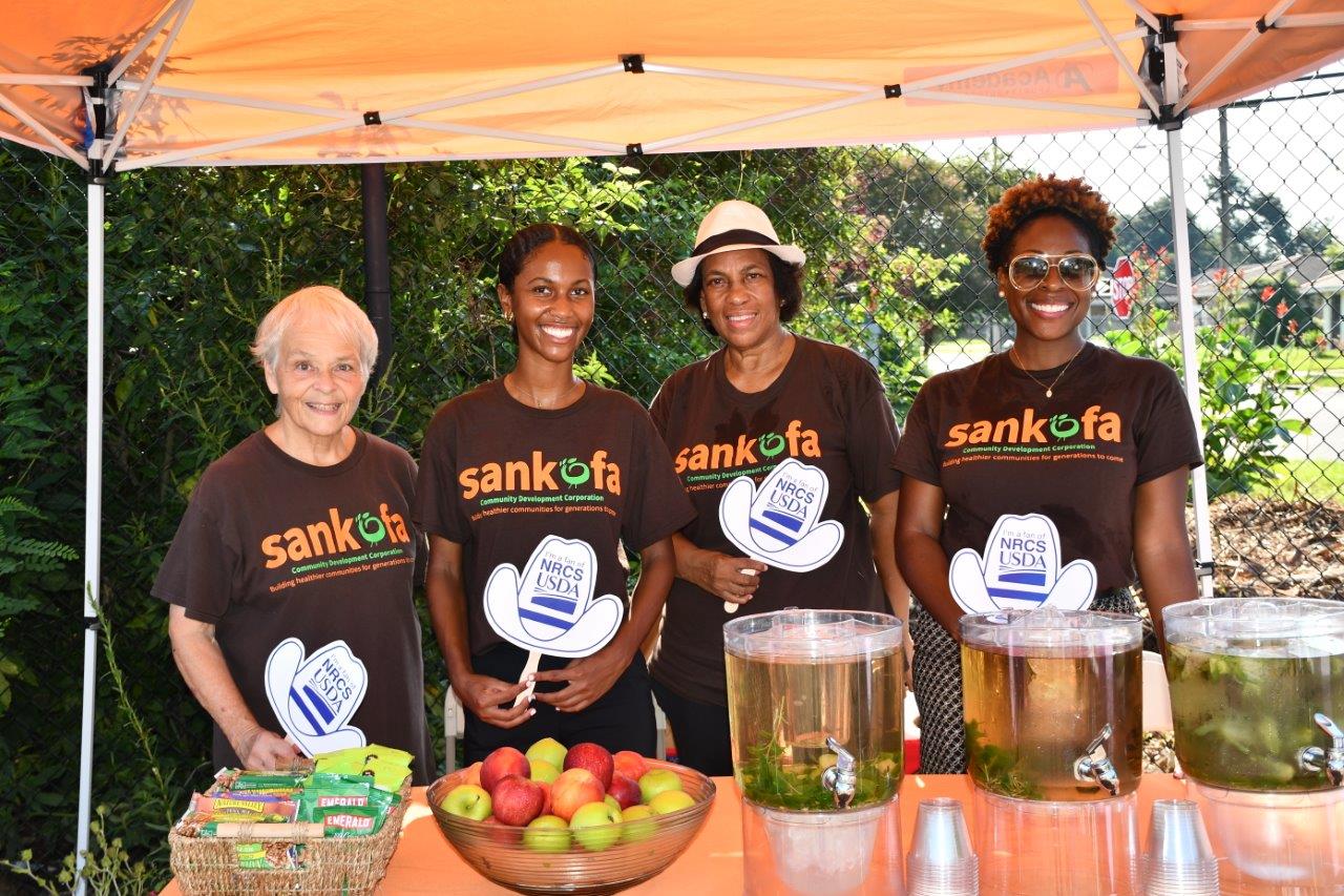 Sankofa employees standing under a tent with food in front of them