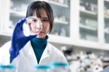 A scientist looking at a vial