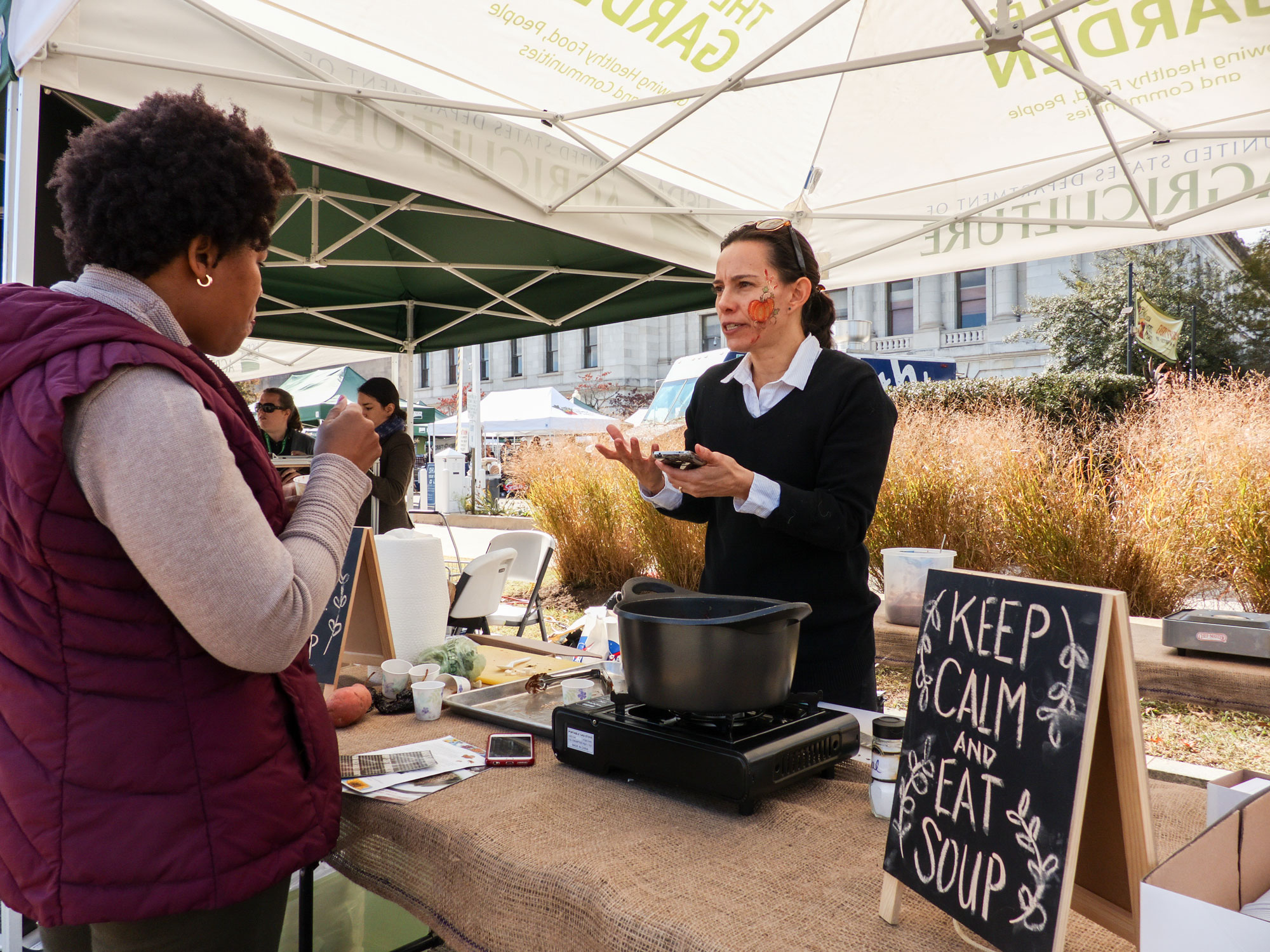 Chef Eliza Gonzalez talking to a visitor about her Roasted Butternut Squash with Ancho Mole at the USDA Farmer's Market